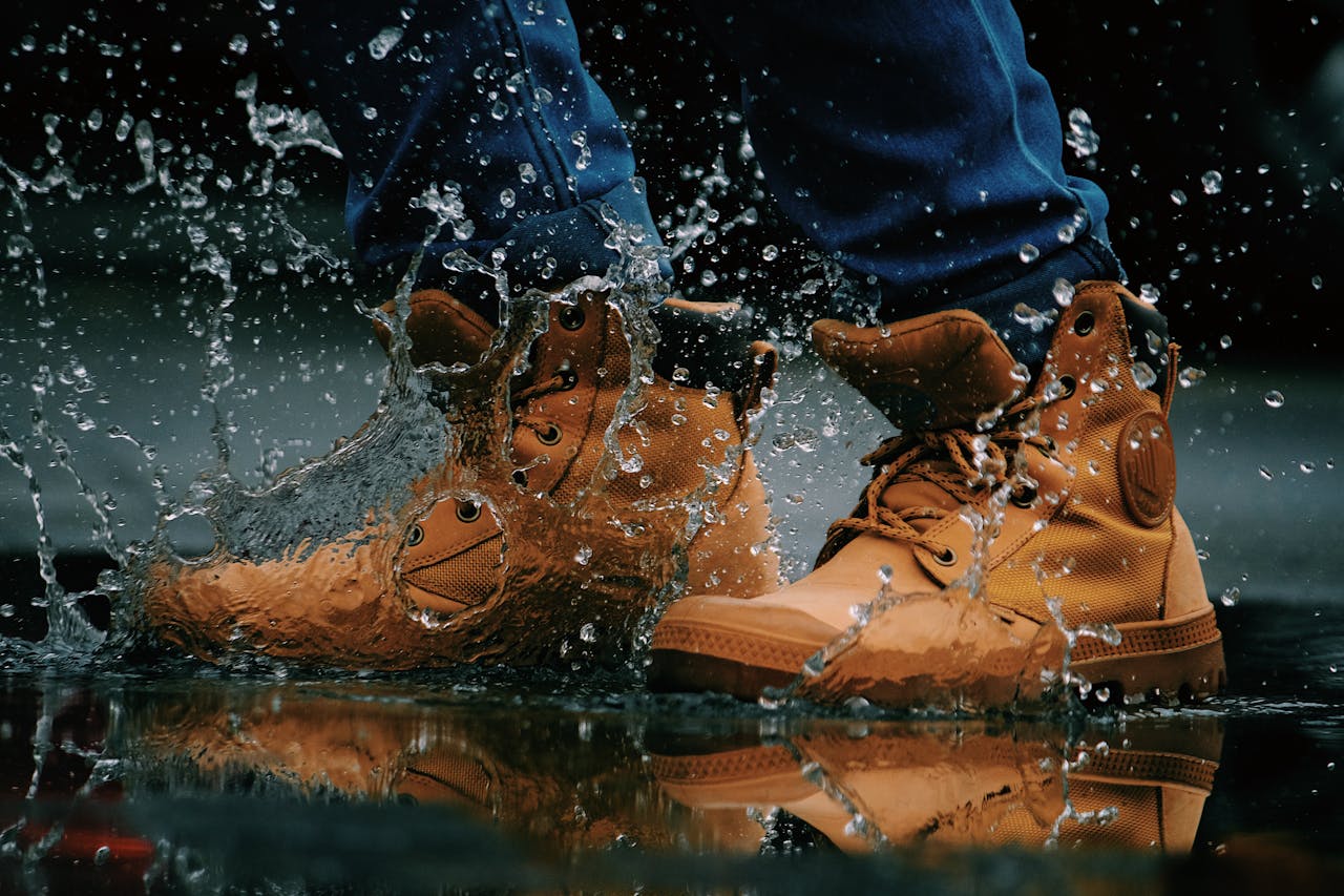 Close-up of hiking boots splashing water in a puddle outdoors