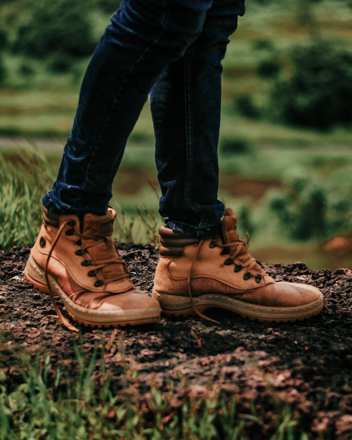 Close-up of brown leather hiking boots on a muddy trail. Outdoor adventure concept.